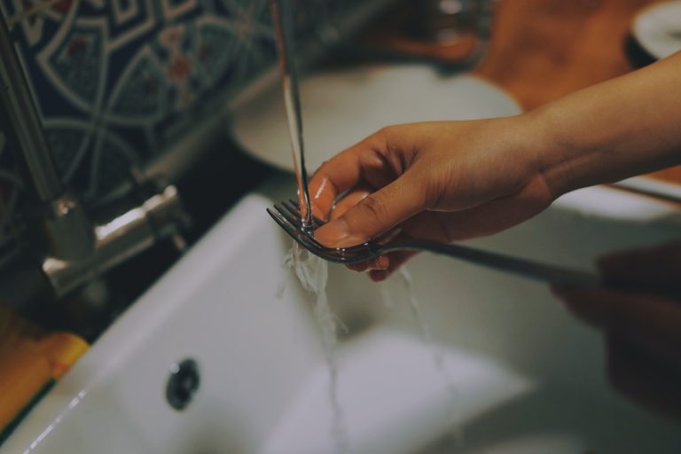 Housekeeper washing a fork with water